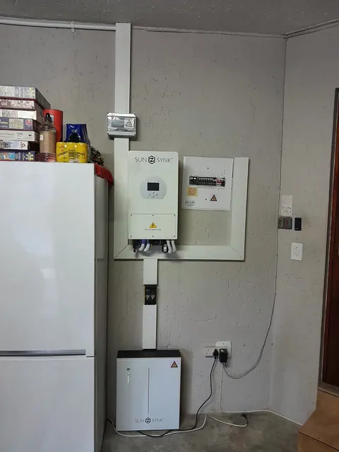 Inverter and battery installation beside a fridge in a room